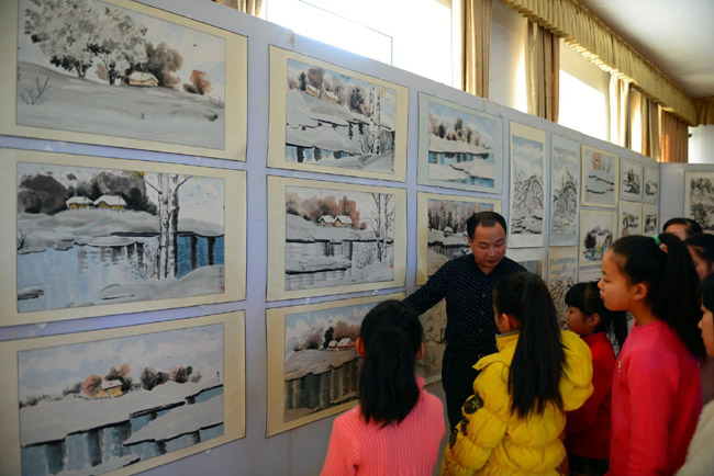 王文举老师在逊克县中小学生展出冰雪画时为学生点评作品